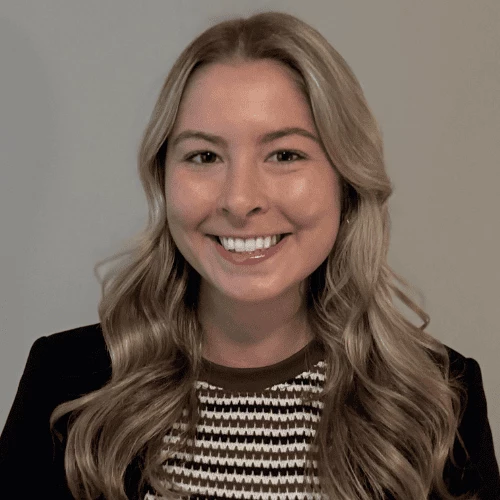 Elena Pomponio, an attorney with Rising for Justice, smiling to camera. Photo shows a young woman with long blonde hair smiling while wearing a black blazer and a striped sweater.